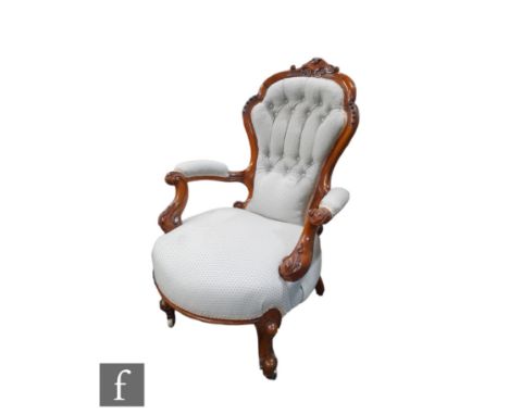 A Victorian carved walnut framed easy elbow chair, shaped back over scroll arms, upholstered in pale blue button back fabric,