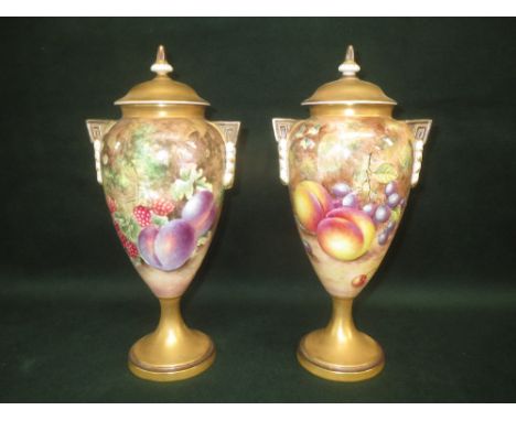 Pair of Royal Worcester bone china, urn shaped vases and covers, each painted with fruit, on a mossy ground, signed Freeman, 