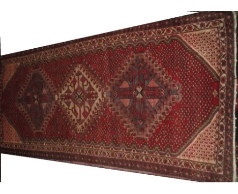 Shiraz carpet, red ground with three large central medallions within pelmet design border