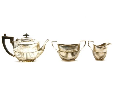 An Edwardian silver three piece tea set, Birmingham, 1902, C.H, of half reeded form, the teapot measuring 17cm high, approxim