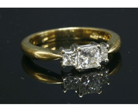 An 18ct gold, three stone, graduated princess cut diamond ring, claw set to a white head to solid tapering shoulders and a pl