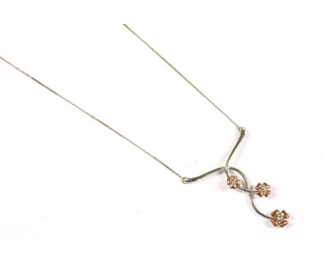A 9ct white gold spray pendant, each flower set with a single brilliant cut diamond and faced in rose gold, suspended on a 9c