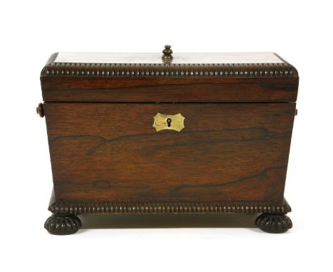 A 19th century gadrooned rosewood tea caddy, of sarcophagus form on bun feet, the fitted interior with a cut glass mixing bow