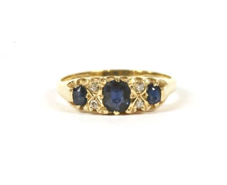 An 18ct gold carved head three stone sapphire ring, with diamond set points, size R½, 3.88g