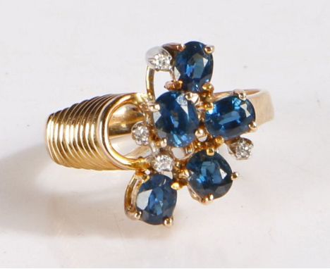 14 carat gold and diamond ring, the head set with five claw mounted blue stones and four diamonds, the band with a spring des