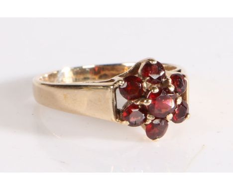 9 carat gold and garnet ring, the head in the form of a flower set with seven claw mounted round cut garnets, weight 2.7 gram