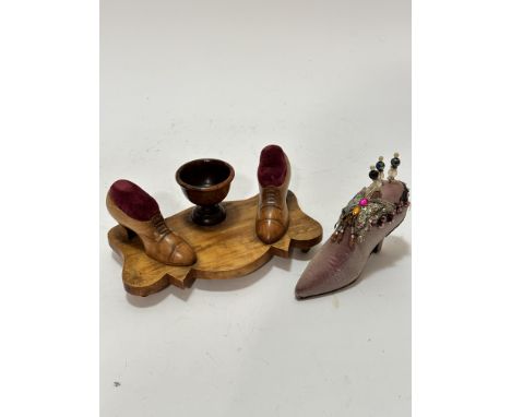 A Continental olive wood shaped pin cushion and bobbin stand with centre egg cup shaped holder, flanked by a pair of treen sh