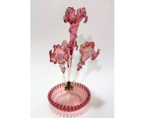 An Edwardian pale pink cranberry glass four branch epergne, the centre of iris style design with scrolling leaves and spiral 