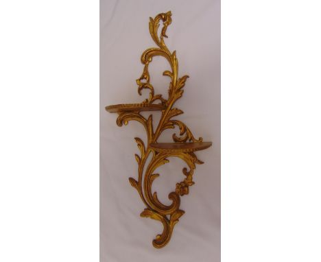 A gilt metal double wall bracket of scrolling leaf design supporting two wooden demi-lune shelves, 66cm (h)