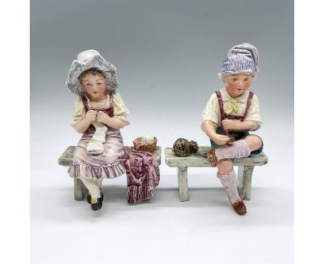 2 hand painted and hand made figures of a young girl and boy seated on a bench. The girl is knitting socks, the boy is fillin