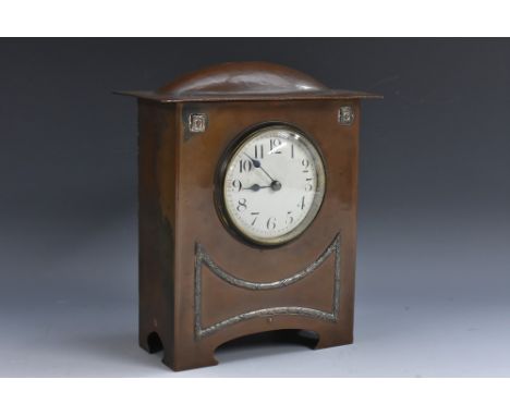 An Arts and Crafts planished copper mantel timepiece, in the manner of Liberty and Co, the domed pediment above a circular wh