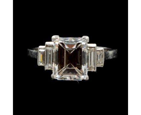 A diamond solitaire ring, the rectangular step cut stone four claw set in an all white metal mount, 1.7mm wide shank marked P