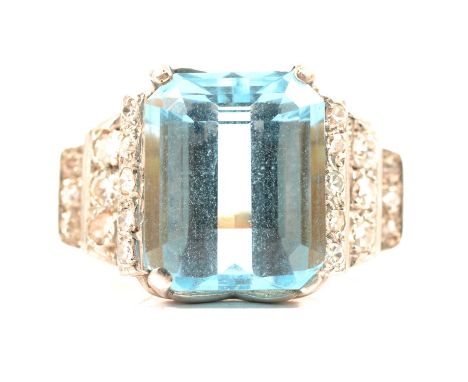 An aquamarine and diamond ring, the rectangular step cut aquamarine four claw set in a yellow and white metal mount with elev