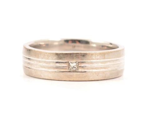 An 18 carat white gold 6mm wide ridged band ring size Q, inset with a small princess cut diamond, Sheffield hallmark, 8.2g.