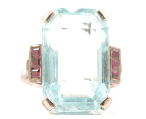 An aquamarine ring with ruby shoulders, the emerald cut aquamarine 20.5x13mm four claw set in an all white metal mount ring s