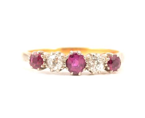 A ruby and diamond half hoop ring, three round faceted rubies and two old cut diamonds claw set in a yellow and white metal m
