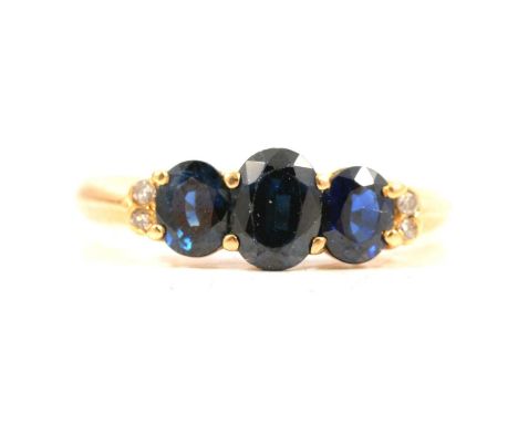 A sapphire and diamond ring, three oval mixed cut sapphires, the centre sapphire approx. 6.3mm x 4.7mm, with another sapphire