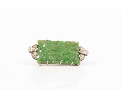 A jade and diamond brooch, a rectangular carved jade panel, 22x15mm claw set in a white metal mount, one brilliant and three 