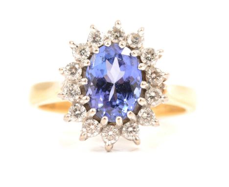 A tanzanite and diamond cluster ring, an oval mixed cut tanzanite 8x6.5mm, claw set and surrounded by fourteen brilliant cut 