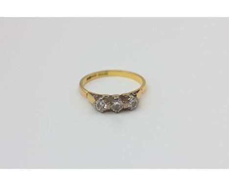 A diamond three-stone ring, the uniform brilliant cuts claw set in 18ct white on yellow gold