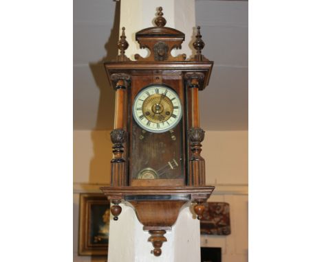 A Vienna style walnut wall clock with 14cm circular dial, enamel chapter ring, in glazed case with surmount and finials, 74cm