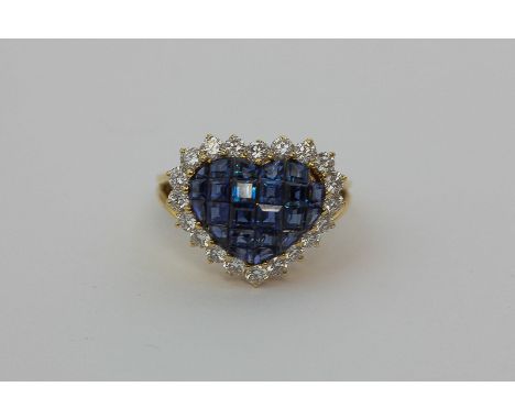 A sapphire and diamond ring, heart shaped, the central panel set with square cut sapphires within a border of brilliant cut d