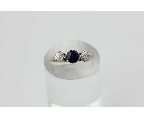 A sapphire and diamond three-stone ring, claw set with old cut diamonds and a central round sapphire