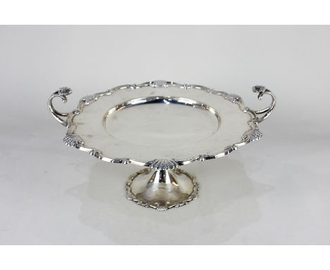 A George V silver tazza, circular top with scroll and shell border and two scroll handles mounted with shells, knapped suppor