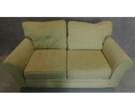 A two seater sofa in cream upholstery. 70x175x90cm 
