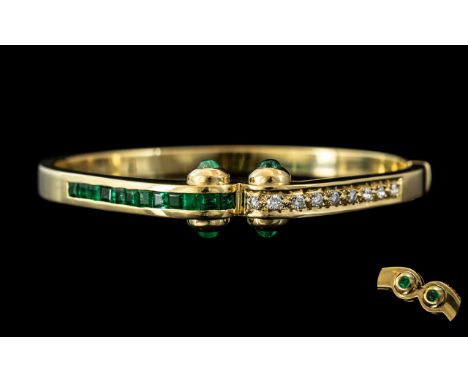 An 18ct Gold Emerald and Diamond Hinged Bangle the front set with calibre cut emeralds and round modern brilliant cut diamond