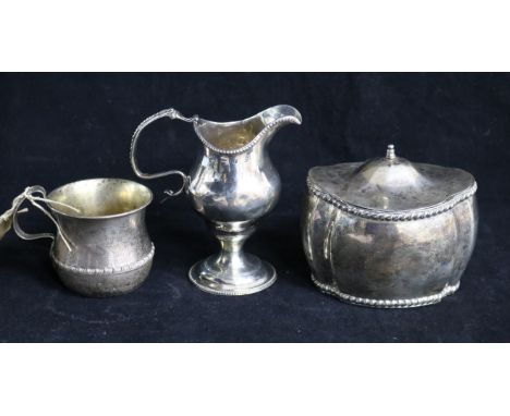 A silver tea caddy, silver cream jug and Indian silver mug.