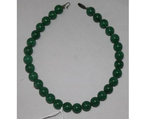 A necklace of thirty polished green jade beads, 14.25in.