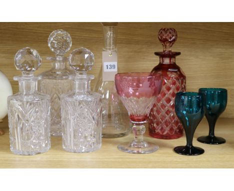 A ruby overlaid glass decanter, four other decanters and three glasses