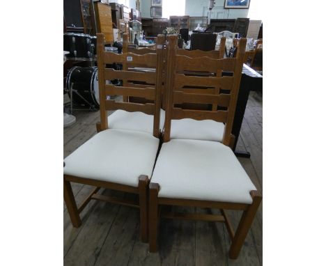 A set of four heavy oak ladder back dining room chairs with cream upholstered seats 