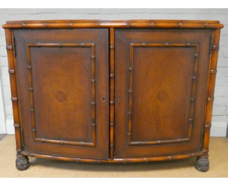 Mahogany bow front bamboo effect two door cupboard standing on carved feet with inset brown tooled leather top, 3'9 wide 