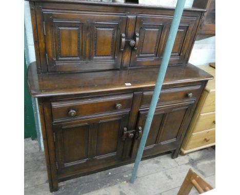 A reproduction Ercol oak court cupboard with a sliding cupboard back, drawers and cupboards under 4' wide 