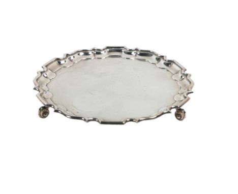 A Sheffield silver circular Salver, c. 1937, with a Chippendale border and supported on three scroll leaf wrapped feet, by Th