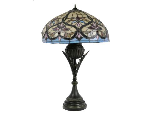 A Tiffany style stained glass Lamp, with domed shade of cream, blue and pink colouring, on a tubular shaped urn design metal 