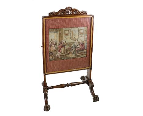 A Victorian mahogany framed tall Firescreen, with carved cornice, inset with a needlework depicting ladies of leisure in an o