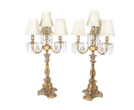 A pair of assimilated giltwood three branch - four light Candelabra, (converted) each with cream shades and glass drops appro
