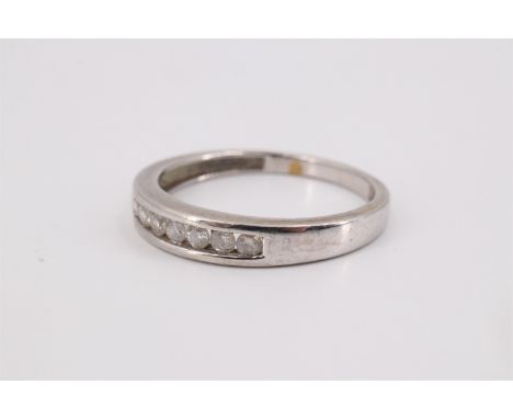A contemporary diamond and 9 ct precious white metal ring, having seven channel-set brilliants between plain tapering shoulde