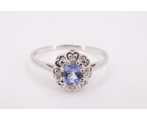 A modern aquamarine and 18 ct white metal ring, the 4 x 5 mm blue stone daisy set on a gallery having four white stones separ