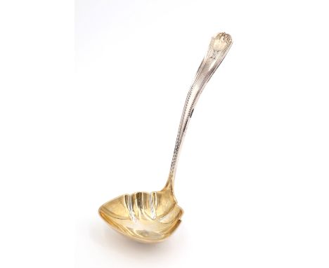 An early 20th Century American white metal sauce ladle, having a parcel gilt scalloped bowl, the terminal bearing an engraved