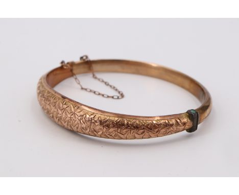 An early 20th Century 9 ct yellow metal hinged bangle, of D-section and decorated with foliate brightwork, 57 mm x 48 mm inte