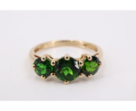 A 9 ct gold green stone ring, having a central 6 mm brilliant flanked by two 5 mm brilliants, set on a gallery between open s