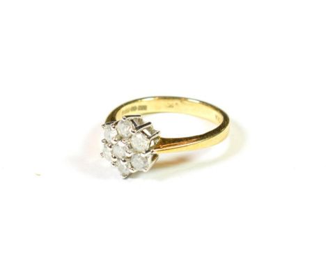 An 18 carat gold diamond cluster ring, the central raised round brilliant cut diamond within a border of round brilliant cut 