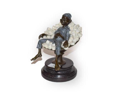 A cold painted bronze figure of an elf reclining asleep in a stemmed bowl of white marshmallows, 20cm high.  No condition iss