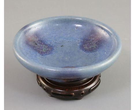 A Chinese Jun type purple-splashed dish, Qing dynasty, unglazed dark brown disc foot, D. 12.5cm, wood stand, boxedProvenance 