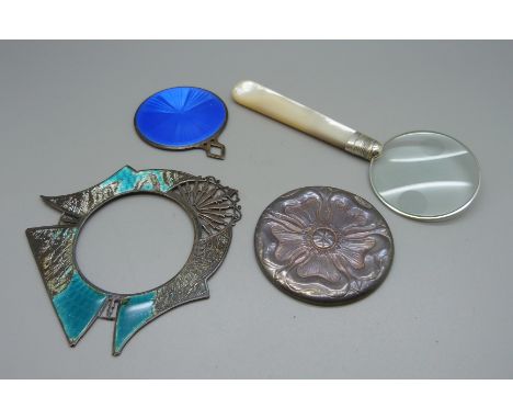 A magnifying glass with mother of pearl handle and silver mount, a silver backed handbag mirror, a silver and enamel handbag 