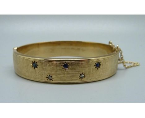 A 9ct gold, sapphire and diamond bangle, 24.7g, marked 'wax filled', inner measurement 55mm x 62mm, with presentation box 